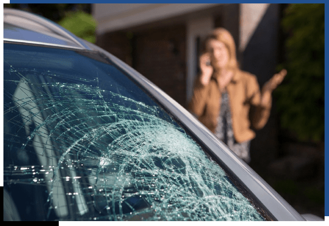 A woman on the phone in front of a car.