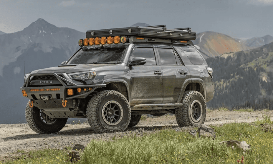 A silver 4 runner with an orange light bar on top.